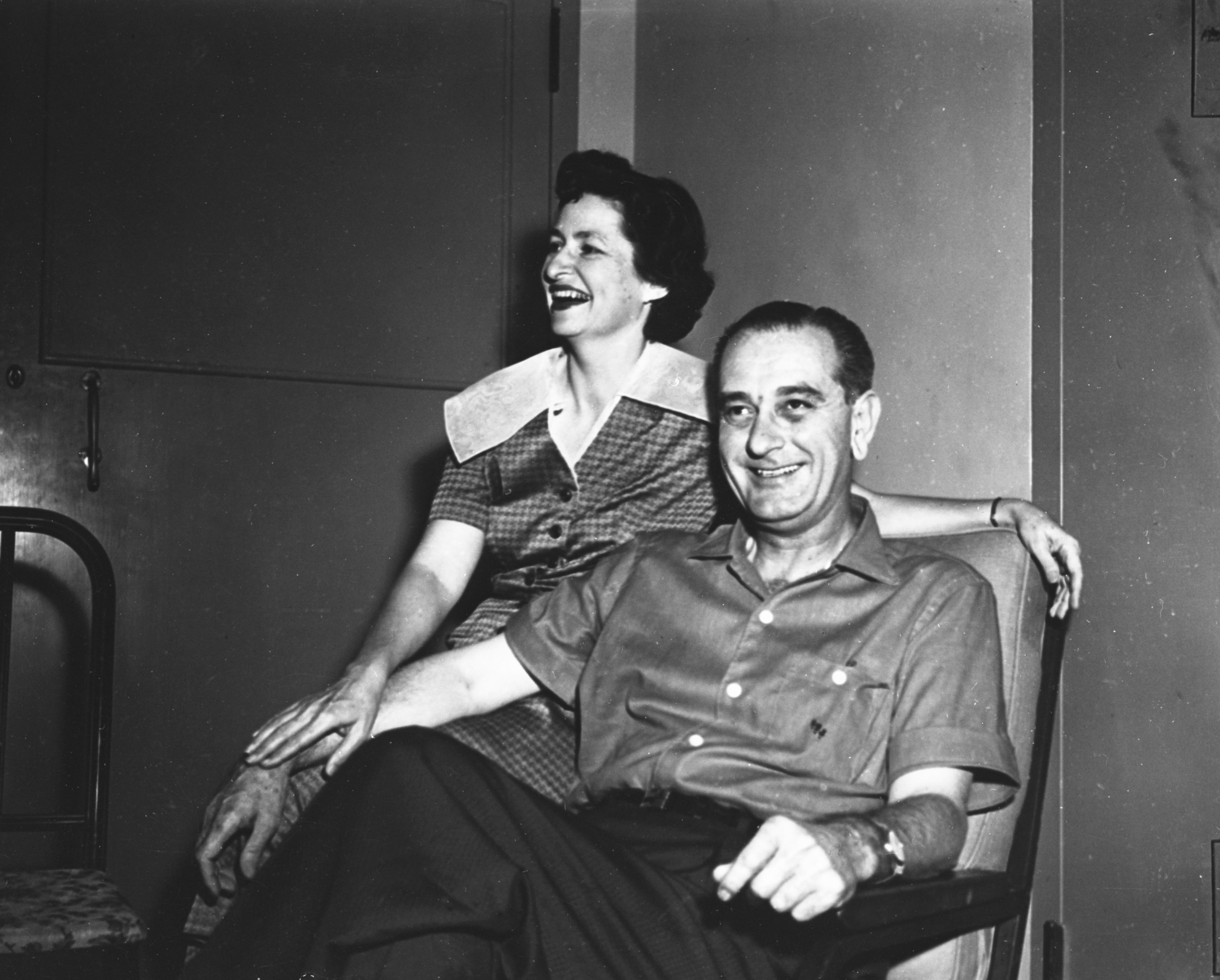 Sen. Lyndon B. Johnson sitting in a chair, Lady Bird Johnson sitting on arm of the chair, smiling for the camera
